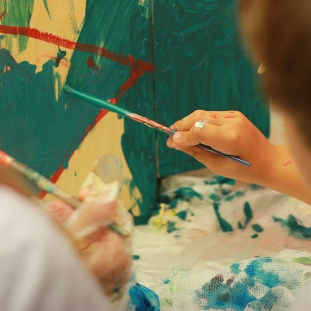 person holding paint brush painting on white and blue floral textile