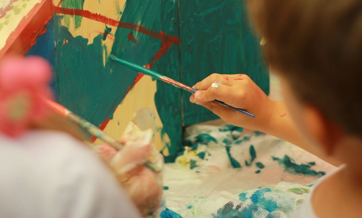 person holding paint brush painting on white and blue floral textile